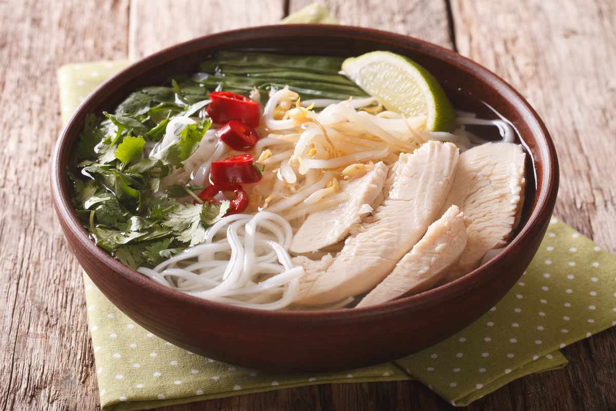 Vietnamese cuisine: soup Pho Ga with chicken, rice noodles and fresh herbs in a bowl