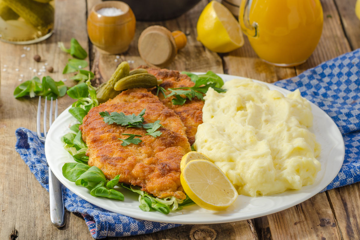Wiener Schnitzel, served with baked potatoes, pickled cucumbers and freshly squeezed orange juice