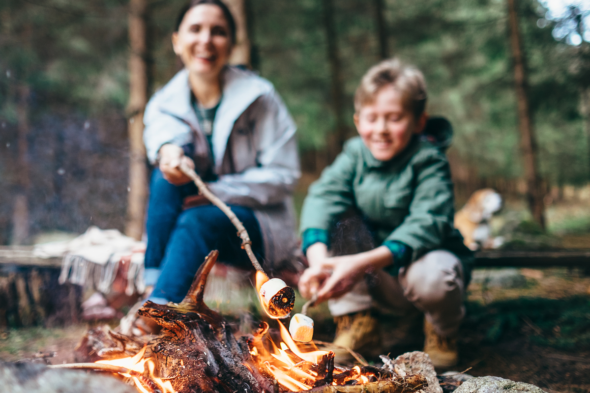 Mother and sun toast marshmallows by campfire