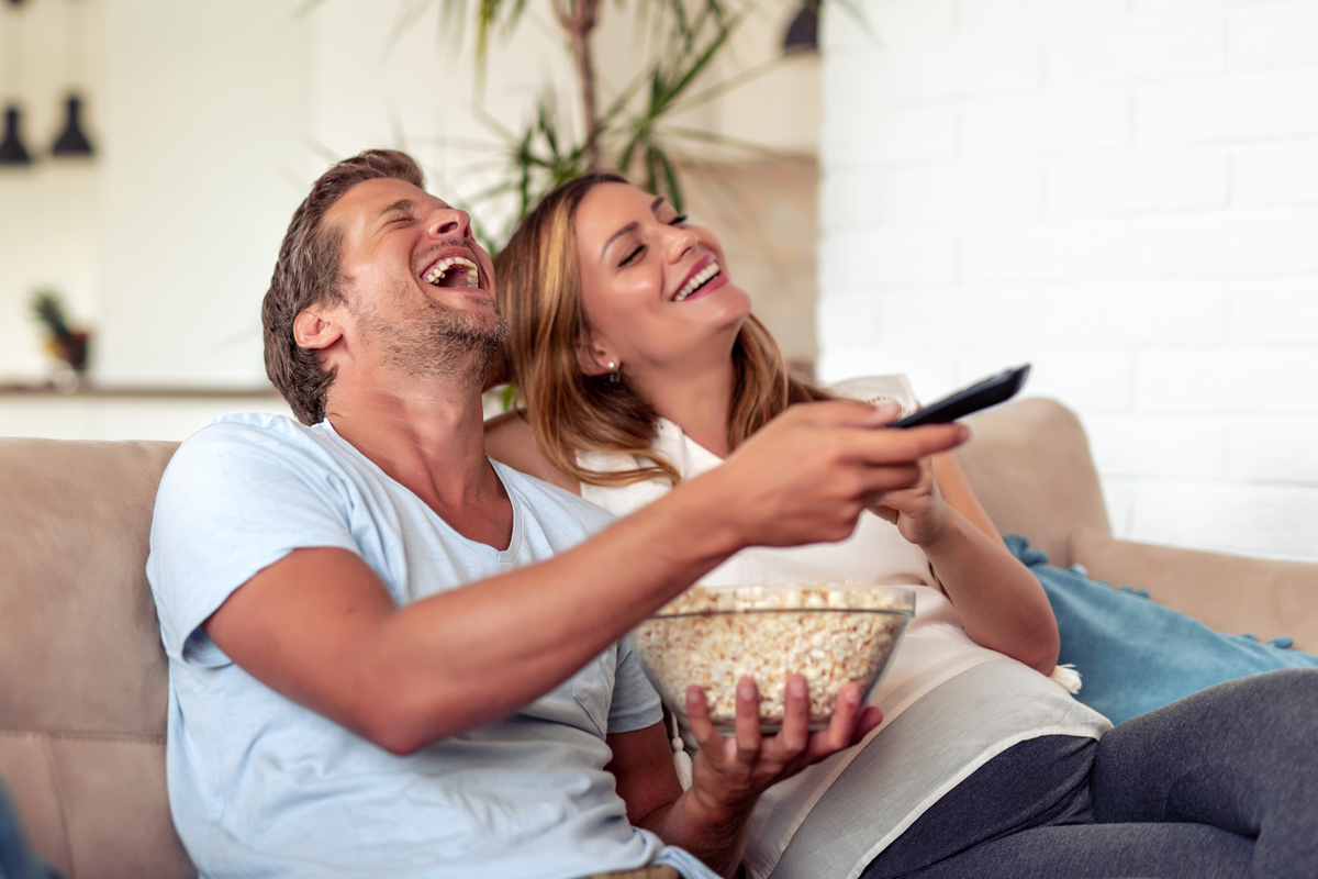 Couple laughing eating popcorn & watching movie
