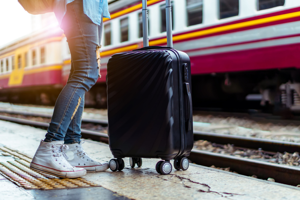 Sturdy suitcase and walking shoes on train platform rail tour